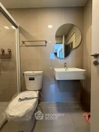 Modern bathroom with unique mirror and sleek fixtures in a contemporary apartment.