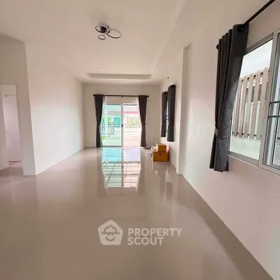 Spacious living room with large windows and modern lighting, perfect for natural light and open living.