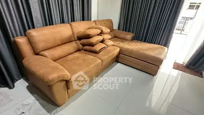 Spacious living room with plush brown sectional sofa and elegant curtains