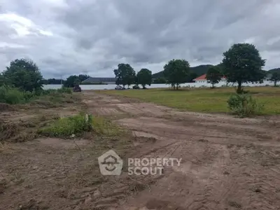 Expansive land plot with lush greenery and distant buildings, ideal for development opportunities.