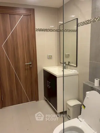 Modern bathroom with sleek design and stylish fixtures, featuring a wooden door and elegant vanity.