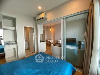 Modern bedroom with blue bedding and open layout to living area