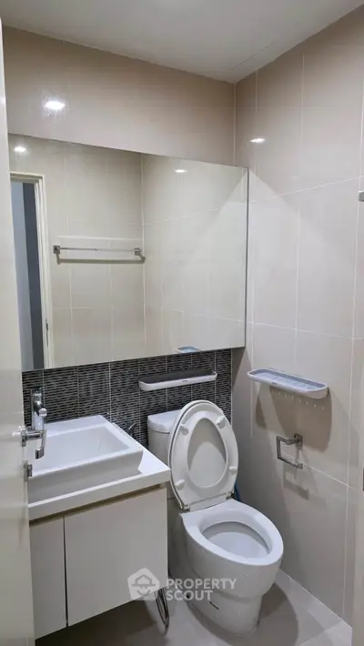 Modern bathroom with sleek fixtures and neutral tiles, featuring a compact design for efficient space use.