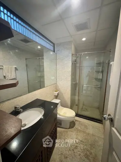 Modern bathroom with glass shower and sleek vanity in a contemporary home.