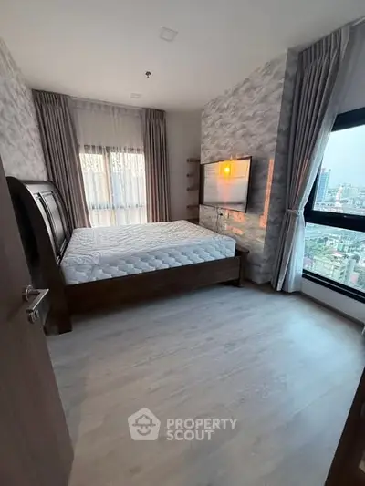 Spacious bedroom with large windows and modern decor in urban apartment.