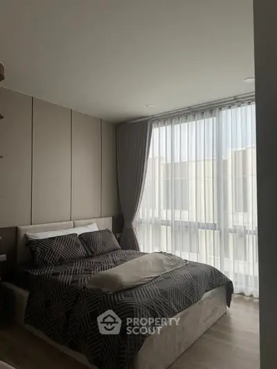 Modern bedroom with large window and stylish decor in a contemporary apartment.