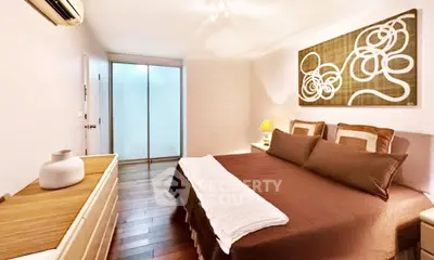 Cozy bedroom with modern decor and wooden flooring, featuring a stylish wall art and ambient lighting.