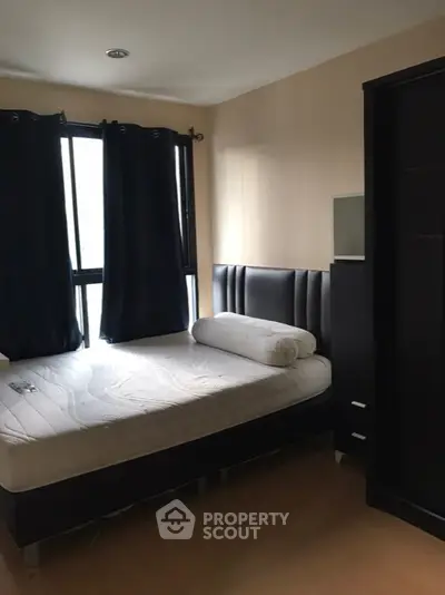 Cozy bedroom with modern furnishings and ample natural light from large windows.