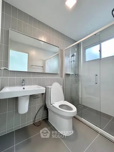 Modern bathroom with sleek design, featuring a glass shower and contemporary fixtures.