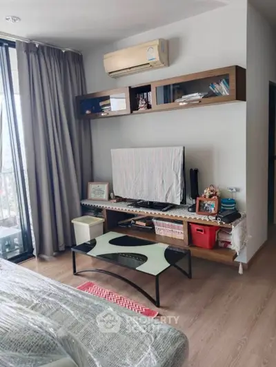 Cozy living room with modern decor and balcony view, featuring air conditioning and stylish shelving.