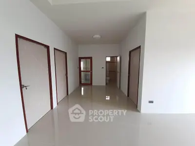 Spacious modern hallway with glossy tiled floors and multiple doors