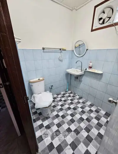 Compact bathroom with tiled floor and wall, featuring a toilet and sink.