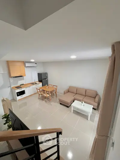 Modern open-plan living room with kitchen, featuring sleek furniture and neutral tones for a cozy ambiance.