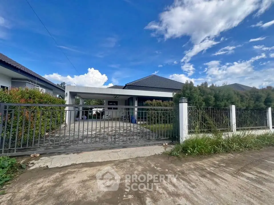 Charming single-story home with spacious driveway and lush greenery under a vibrant blue sky.