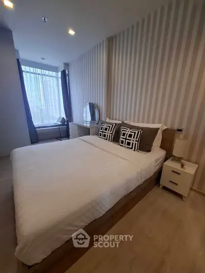 Modern bedroom with stylish decor and large window offering natural light.