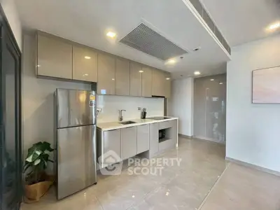 Modern kitchen with sleek cabinetry and stainless steel fridge in a bright apartment.