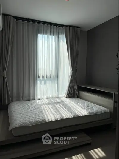 Modern bedroom with large window and stylish curtains, featuring a minimalist bed frame and natural light.