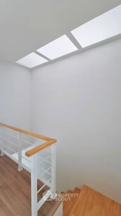 Modern staircase with wooden steps and sleek railing in a bright interior space.