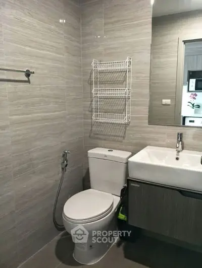 Modern bathroom with sleek fixtures and neutral tiles, featuring a wall-mounted sink and toilet.