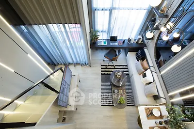 Modern loft-style living room with high ceilings, stylish decor, and large windows for natural light.