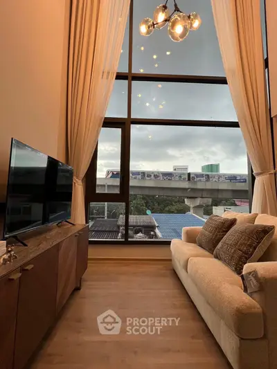 Modern living room with large window and elegant decor, offering a stunning view of the cityscape.