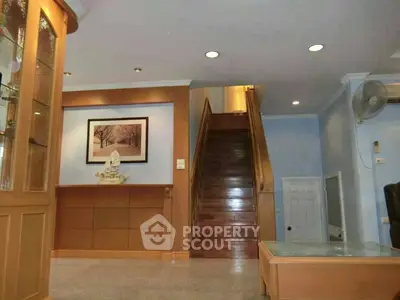 Spacious living area with elegant wooden staircase and decorative elements.
