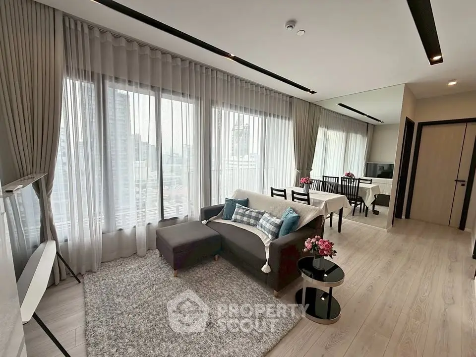 Spacious modern living room with large windows and elegant decor in a high-rise apartment.