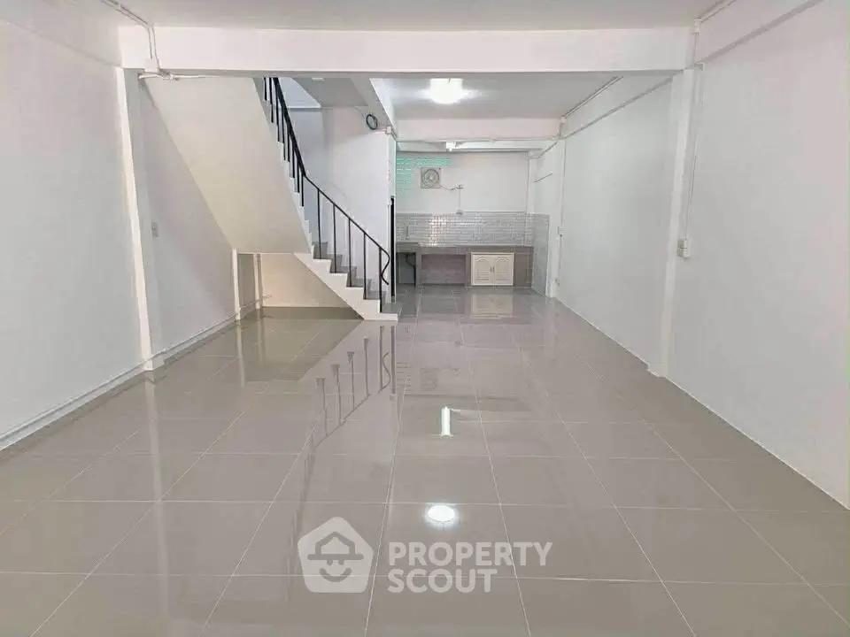 Spacious open-plan living area with sleek tiled flooring and modern staircase.