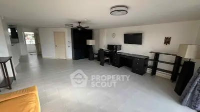 Spacious living room with modern furniture and wall-mounted TV in a bright apartment.