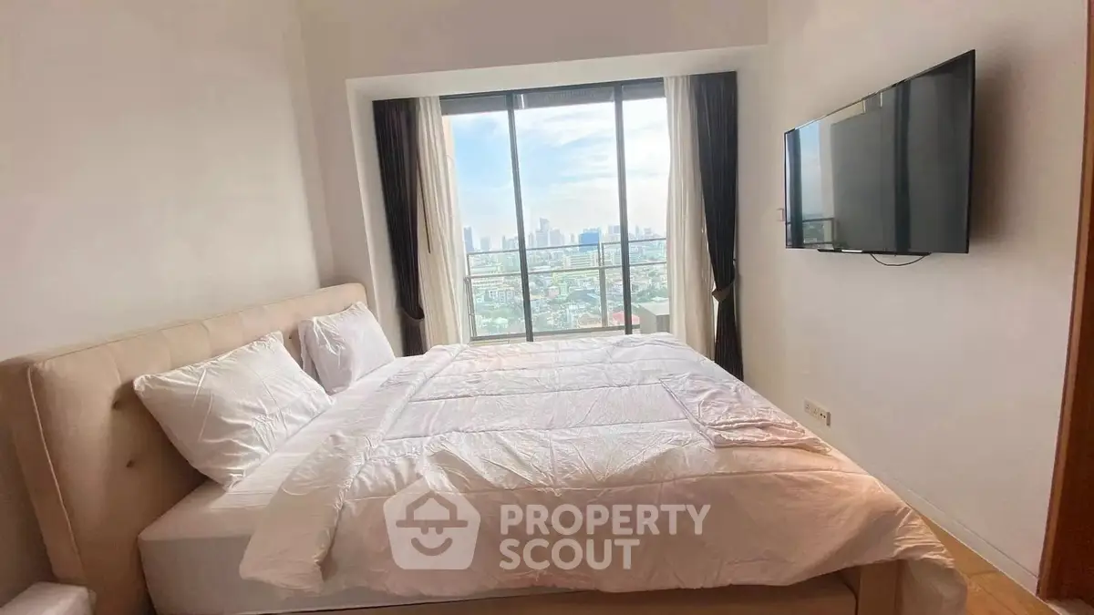 Bright bedroom with city view and wall-mounted TV in modern apartment.