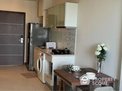 Modern kitchen with dining area, washing machine, and sleek appliances in a cozy apartment.