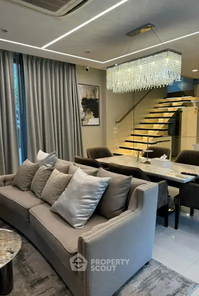 Luxurious living room with elegant chandelier and modern staircase, perfect for sophisticated living.