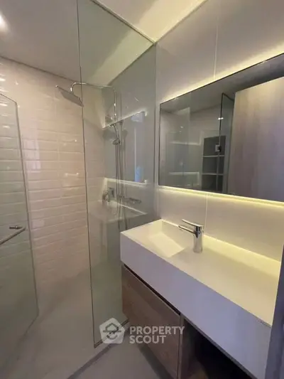 Modern bathroom with glass shower and sleek vanity in contemporary apartment.