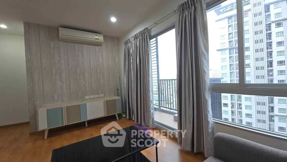 Modern living room with large windows and balcony view in a high-rise apartment.