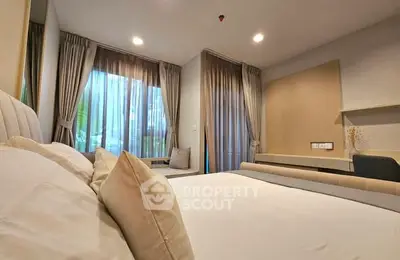 Spacious bedroom with large windows and elegant curtains in modern apartment.