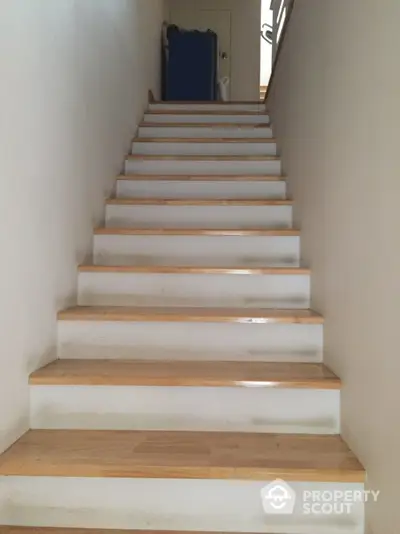 Pristine white staircase with natural wood accents leads to a bright upper level, enhancing the home's modern aesthetic and flow.