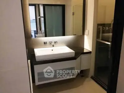 Modern bathroom with sleek sink and large mirror in a contemporary apartment.
