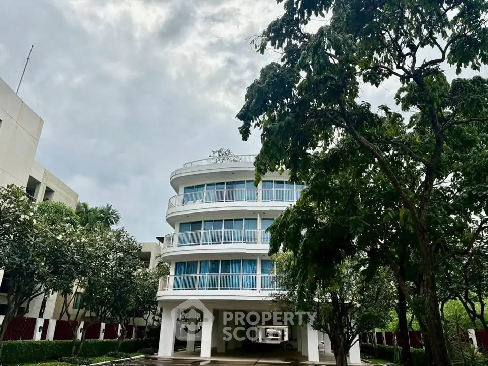 Modern multi-story building with large windows and lush greenery, ideal for urban living.