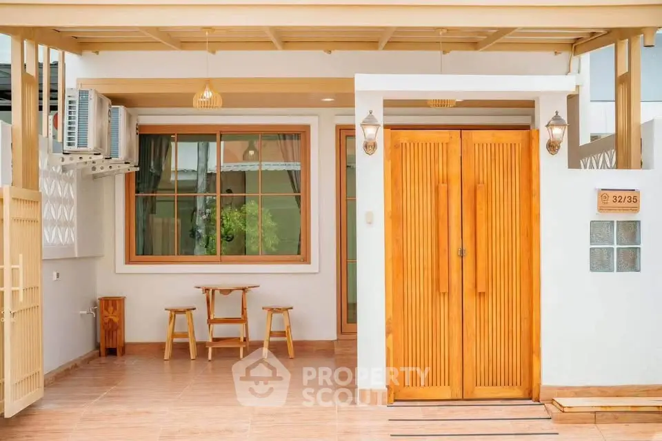 Charming house entrance with wooden doors and cozy outdoor seating area.