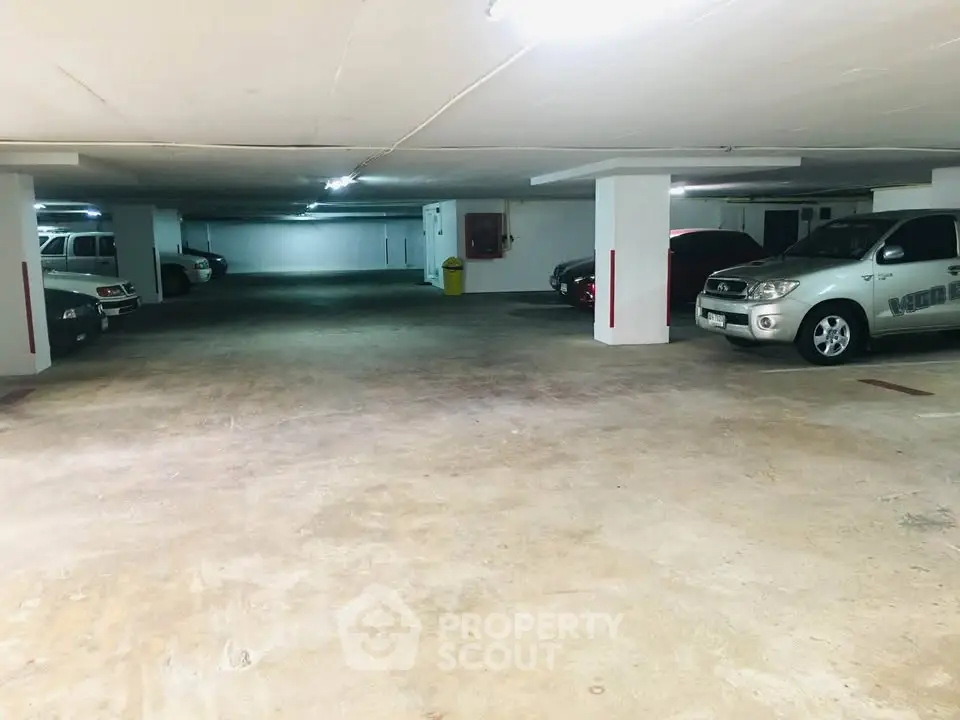 Spacious underground parking area with multiple vehicles parked, well-lit and secure.