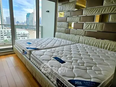 Luxurious bedroom with twin beds and stunning city view from large windows.