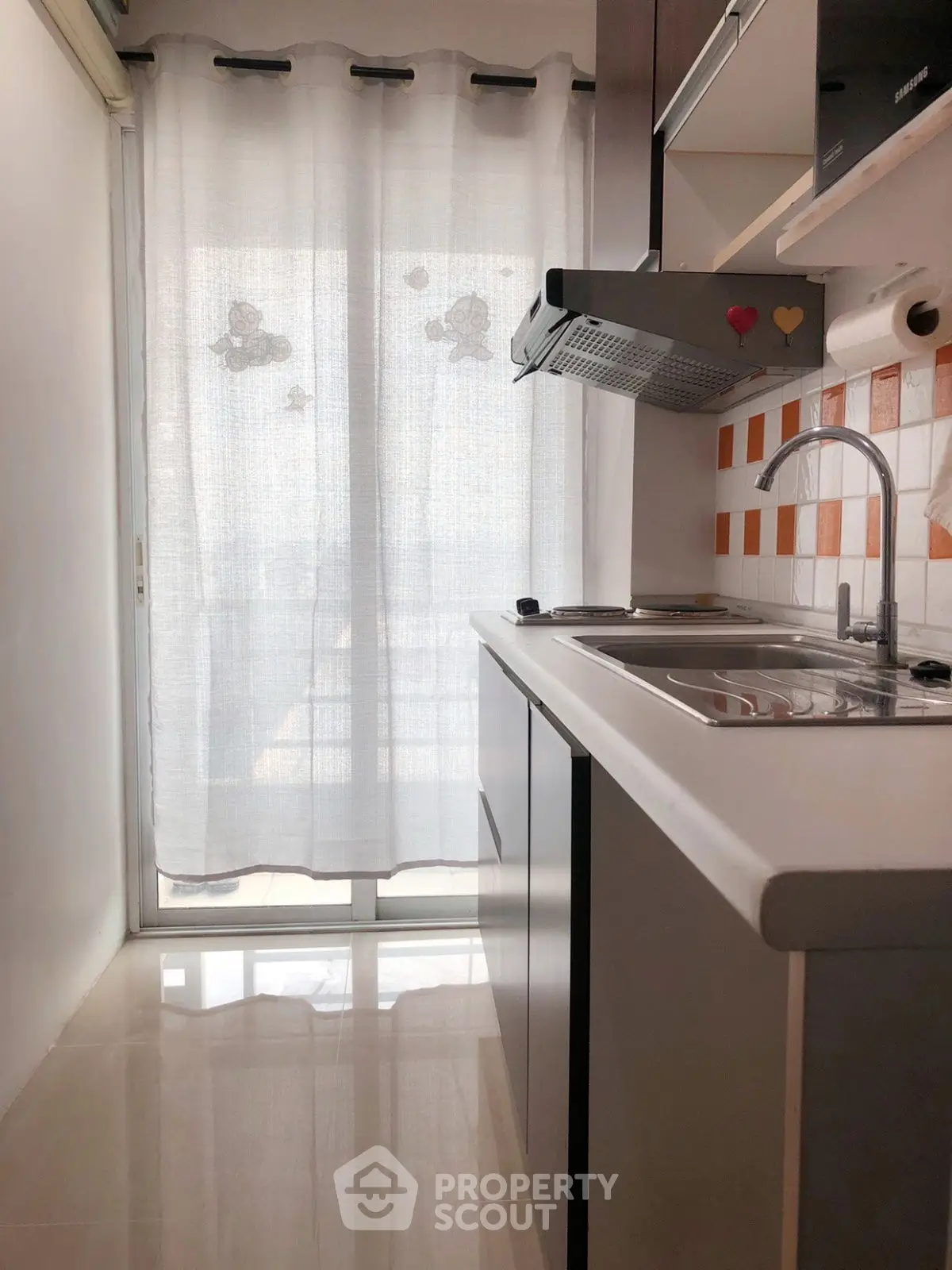 Compact kitchen with modern fixtures and natural light through sheer curtains.