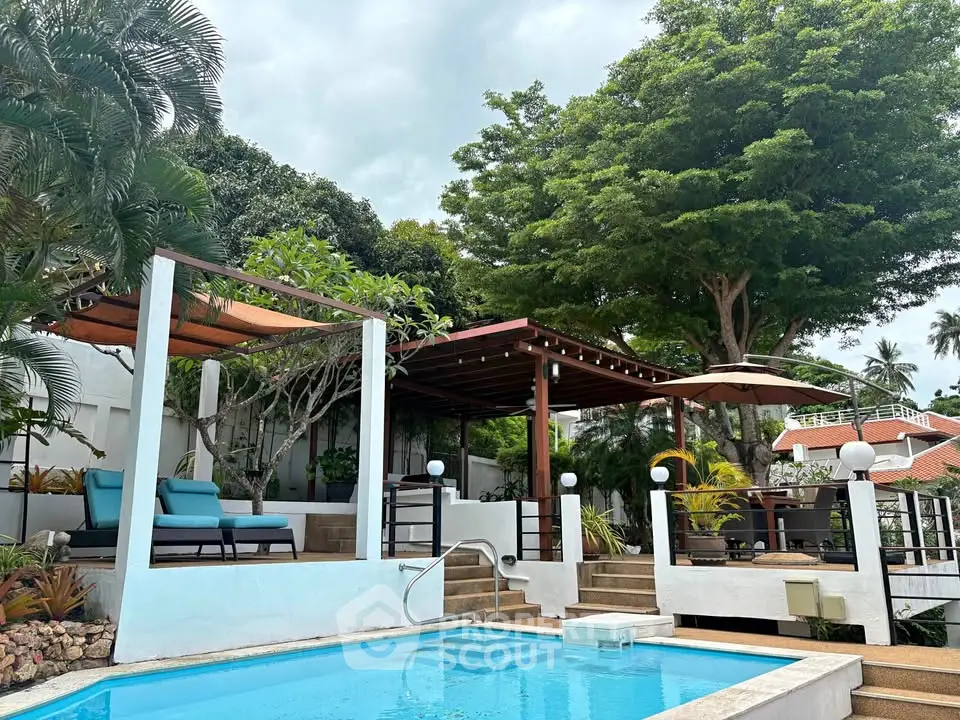 Luxurious outdoor pool area with lush greenery and stylish seating, perfect for relaxation and entertainment.