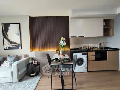 Modern open-plan living room with stylish kitchen and dining area, featuring a washing machine and elegant decor.