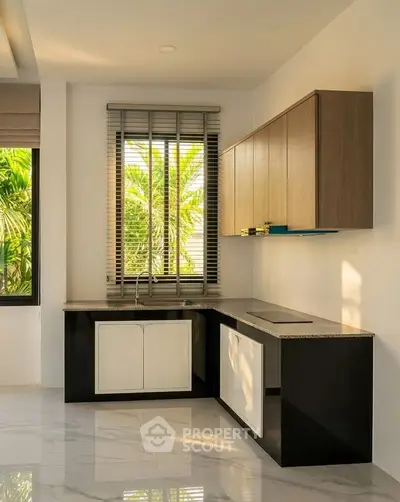 Modern kitchen with sleek cabinetry and large window offering lush garden views.