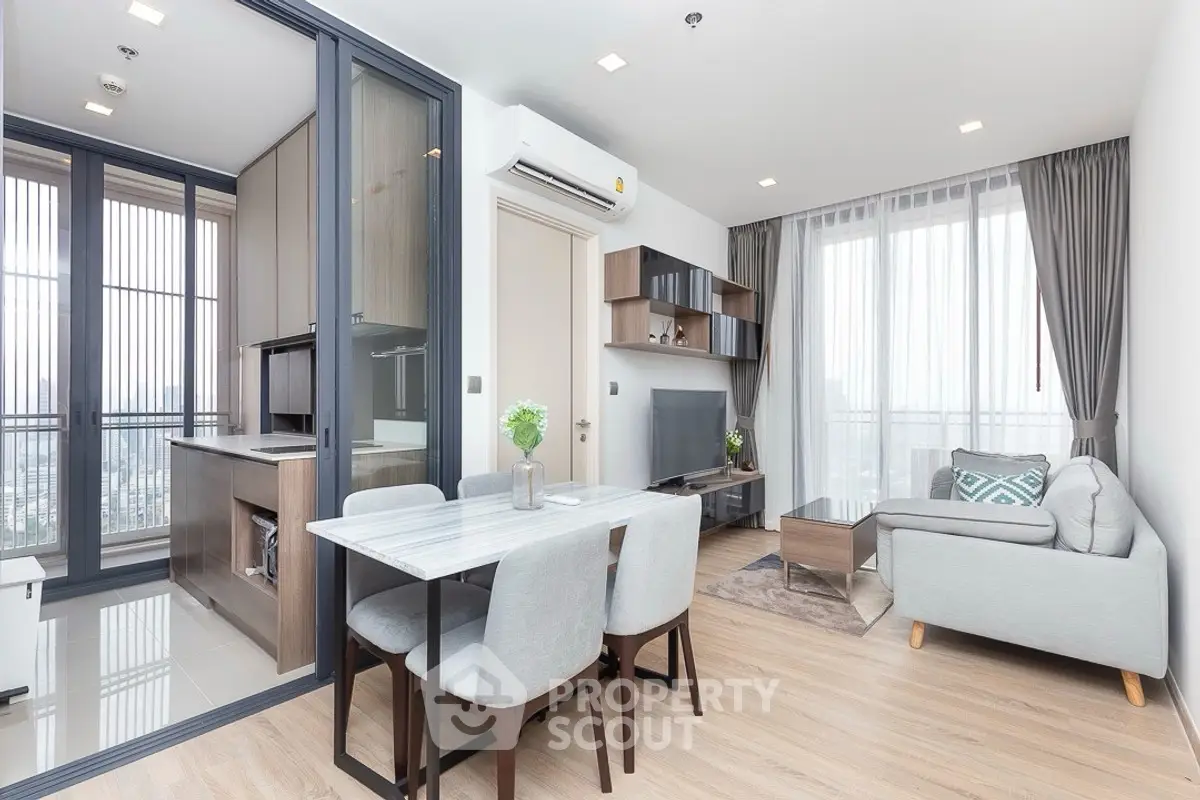 Modern open-plan living room with dining area and kitchen in a bright apartment.