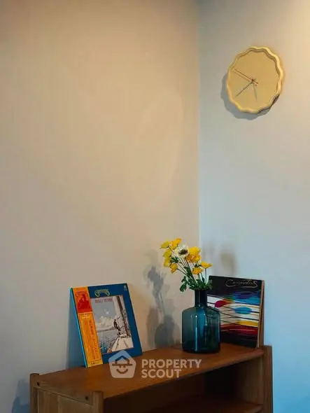 Cozy interior corner with stylish clock and decorative items on wooden shelf.