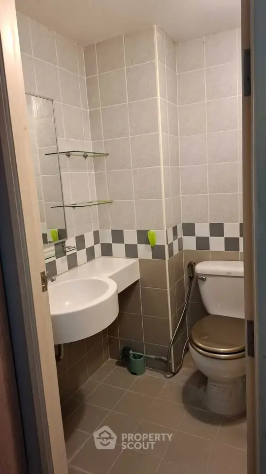 Compact bathroom with modern fixtures and tiled walls, featuring a wall-mounted sink and toilet.
