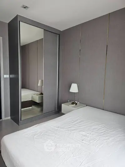 Modern bedroom with sleek mirrored wardrobe and stylish bedside lamp