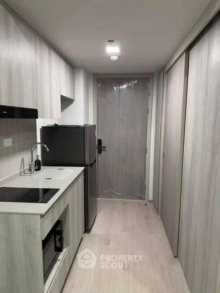 Modern compact kitchen with sleek appliances and minimalist design in a stylish apartment.